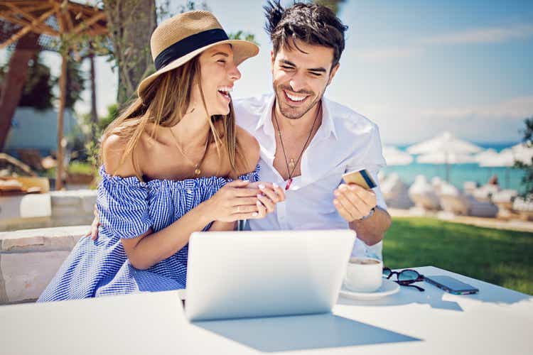 Couple is shopping online/making reservation on the beach