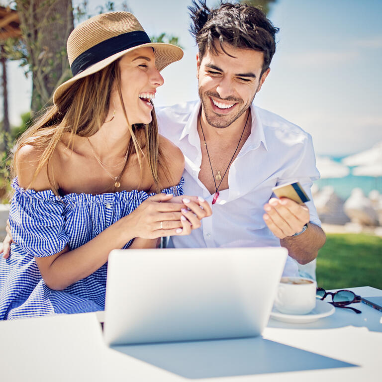 Couple is shopping online/making reservation on the beach