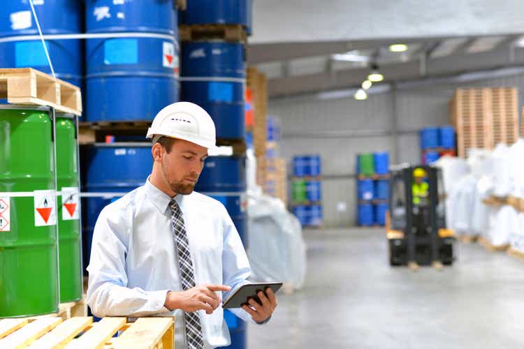 manager in a logistic company work in a warehouse with chemicals - checking goods with tablet