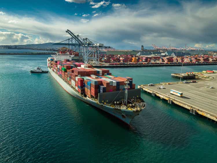 Tug Boat Maneuvering Cargo Ship at Dockside in Port of Long Beach