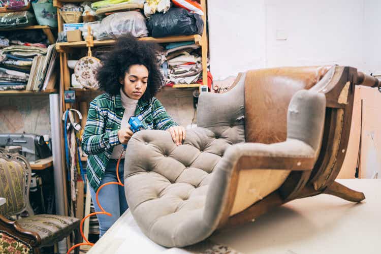 Afro Female Refurbishing Chair In Upholstery Workshop