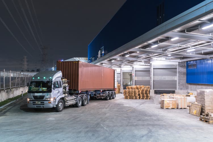 Truck is carrying container is parking in front warehouse at night time