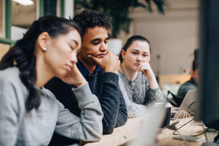 Bored business colleagues sitting at desk in office