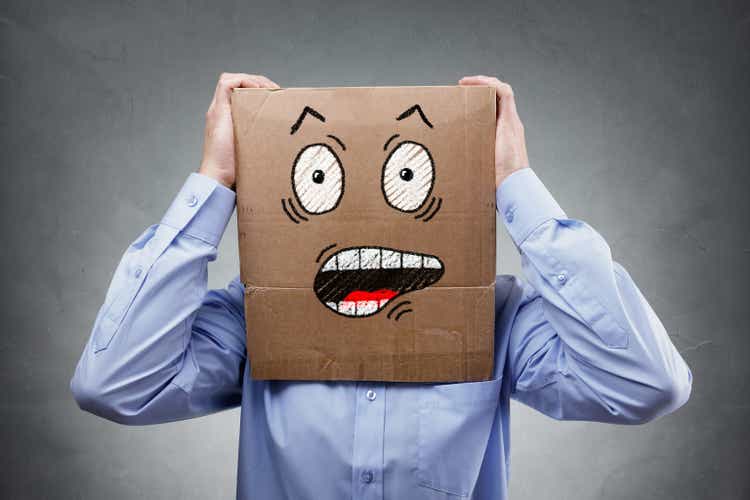 Man with cardboard box on his head showing shocked and surprised expression
