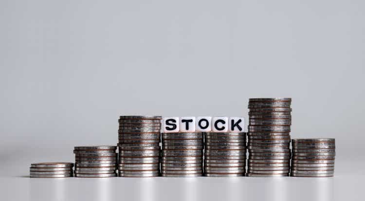 STOCK word written in white cube. Pile of coins in the shape of a graph.