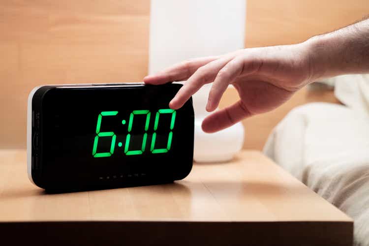 Man reaching to turning off digital alarm clock in the morning at 6.00 a.m.