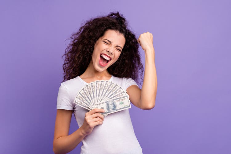 Portrait of her she nice attractive lovely cheerful cheery wavy-haired lady holding in hand big large sum of money best salary interest isolated on bright vivid shine violet pastel background