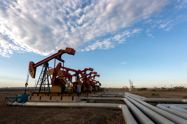 Oil pumping unit in the background of blue sky and white clouds