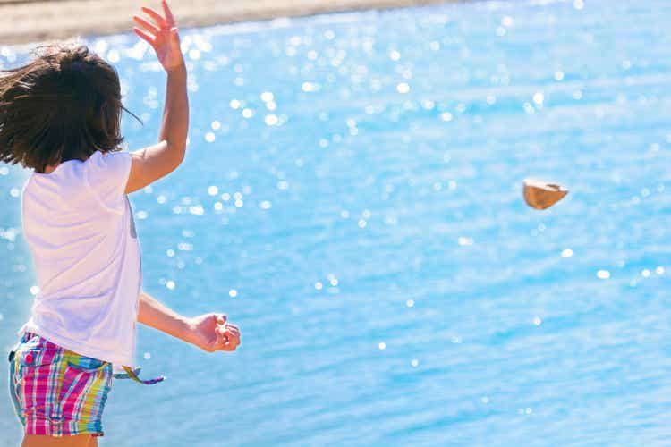 Little girl throws rocks into the water.