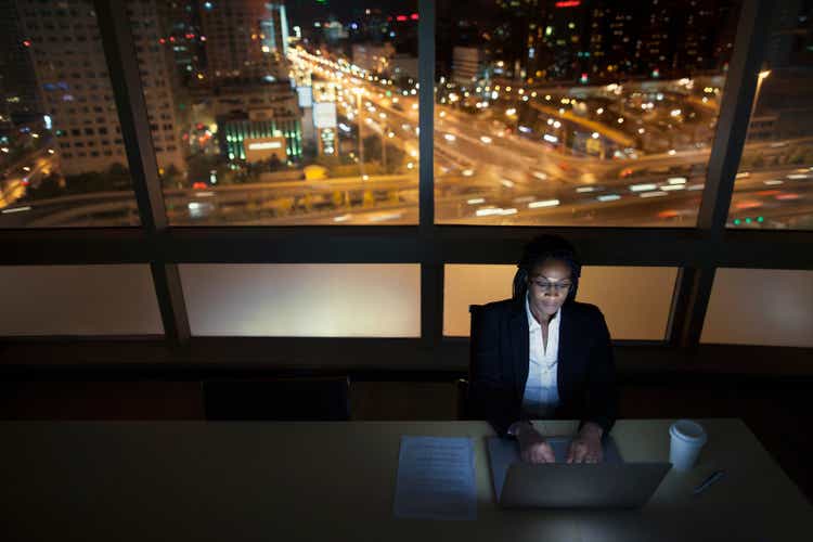 Businesswoman working on laptop at night in office downtown