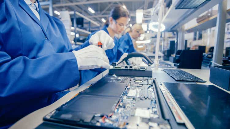Close-Up of a Female Electronics Factory Worker in Blue Work Coat Assembling Laptop