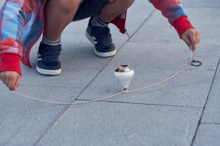 Child catching the spinning top with the rope.