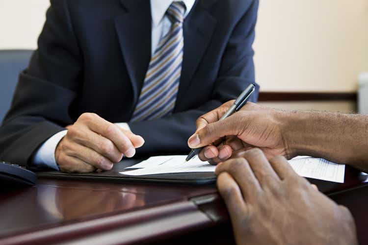 Customer signing paperwork with bank manager