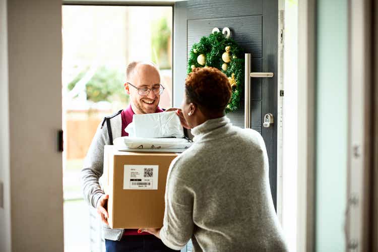 Woman checking delivery with cheerful courier at front door