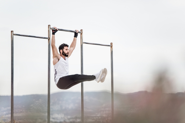 Young athletic man doing an ab workout and pull ups.