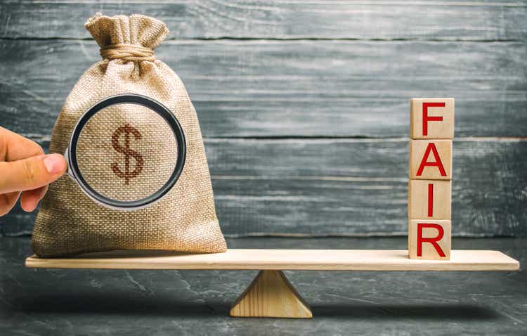Money bag and wooden blocks with the word Fair. Balance. Fair value pricing, money debt. Fair deal. Reasonable price. Justified risk. Honest loan. Secured loans.