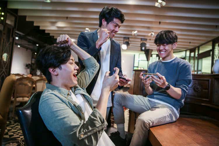 Young friends playing mobile game in cafe