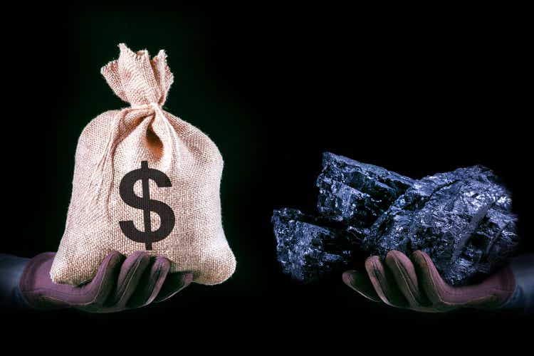 Hand with bag with Dollar banknotes and hand with coal stone. Mining industry concept with dollars and coal