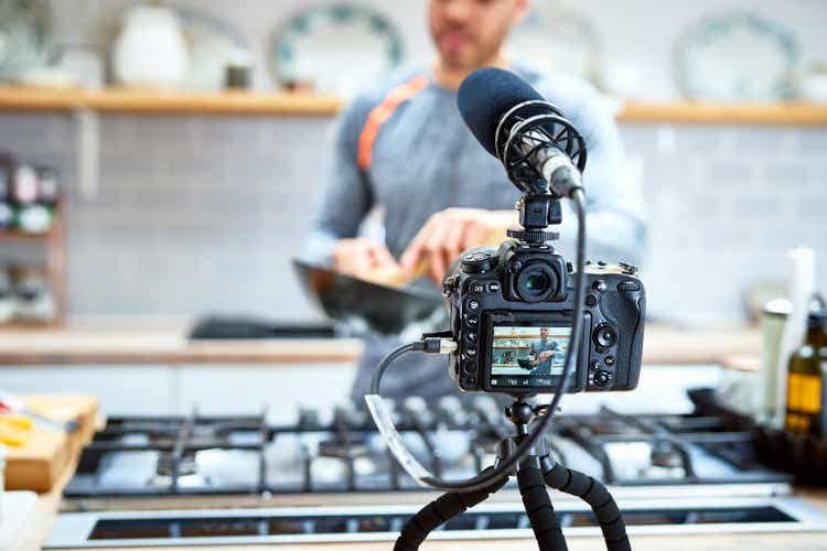 Video camera set up to film man cooking in kitchen