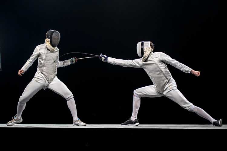 Two fencers fighting in front of a black background