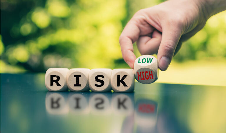 Symbol for reducing a risk. Cubes form the word "RISK" while a hand turns a cube and changes the word "high" to low" (or vice versa).