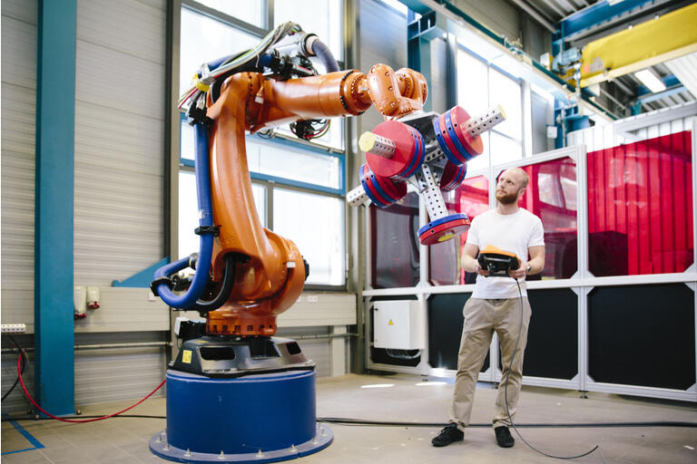industria 4.0: Un joven ingeniero trabaja en un brazo robótico