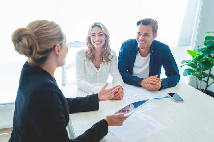 Insurance agent with couple looking through documents.