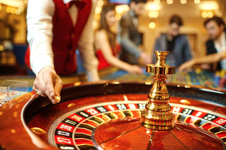 The croupier holds a roulette ball in a casino in his hand.