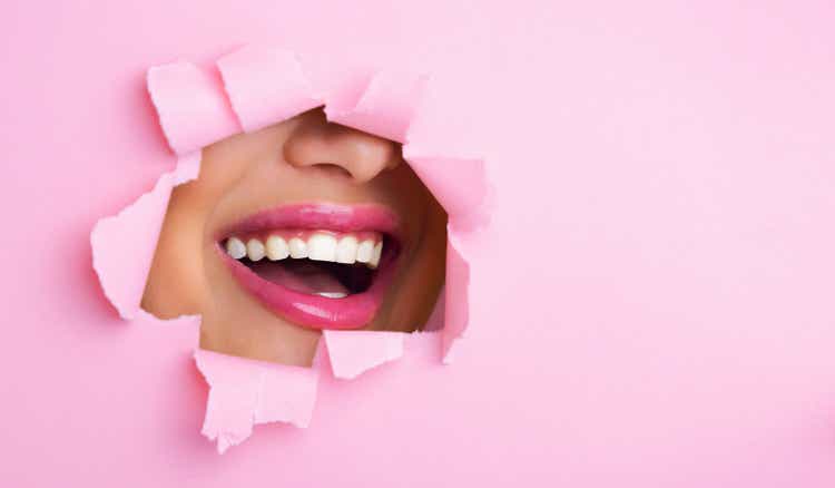 Vrouw glimlachend door gat in roze papier