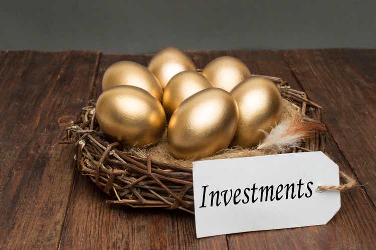 Nest with golden eggs with a tag and a word of investments on a wooden background. The concept of successful retirement