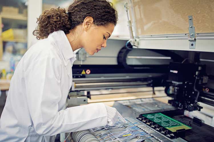 A woman is operating a resistor pick and place machine in a circuit board factory