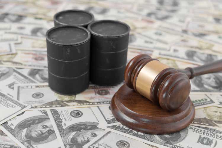 barrels of oil, a judge"s hammer against the background of dollar bills.