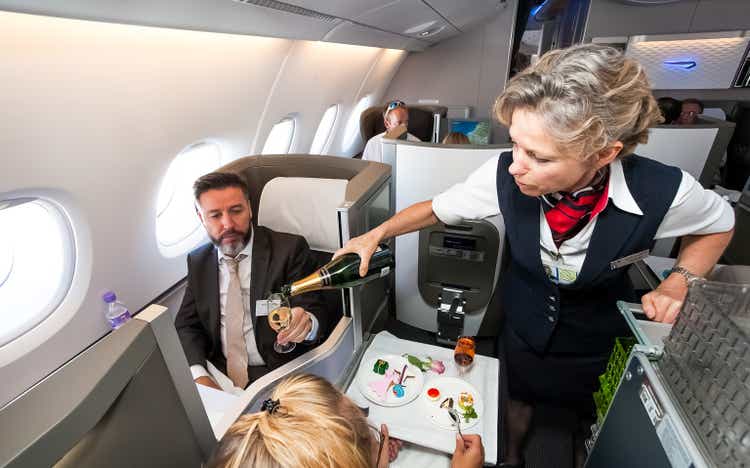 In the Airbus A380 business class, the female crew member is pouring a glass of champagne