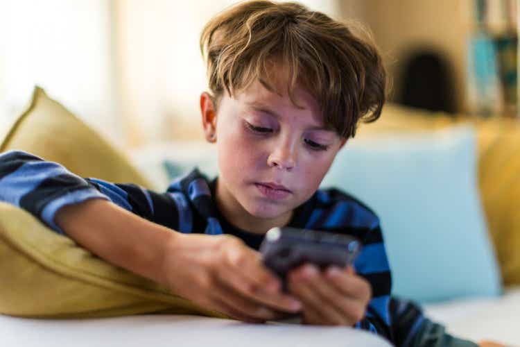 Boy playing alone on smart phone in living room