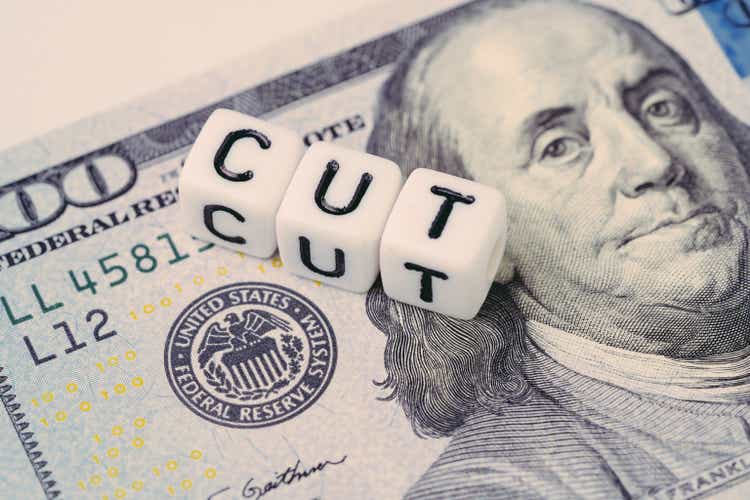 FED, Federal Reserve with interest rate cut concept, small cube block with alphabet building the word CUT next to Federal Reserve emblem on US Dollar banknote