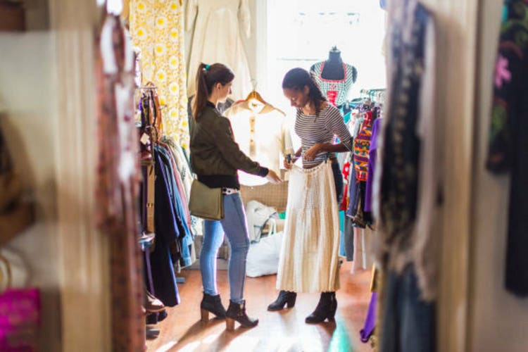Two young women looking at clothes in a vintage clothes shop