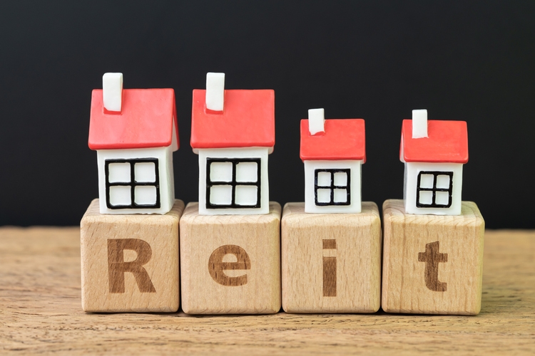 Reit, Real estate investment trust concept, miniature houses on cube wooden block with alphabet combine the word Reit on dark black background