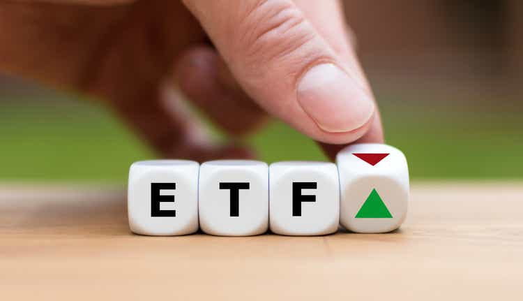 Hand is turning a dice and changes the direction of an arrow symbolizing that the value of an ETF (Exchange Traded Fund) is going up (or vice versa)