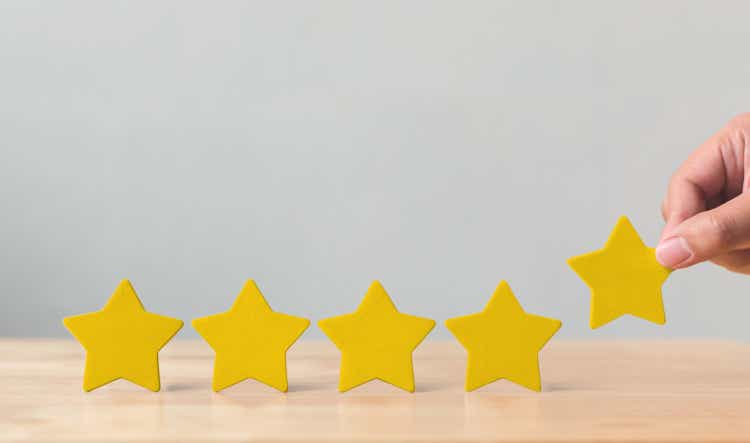 Hand putting wooden five star shape on table. The best excellent business services rating customer experience concept