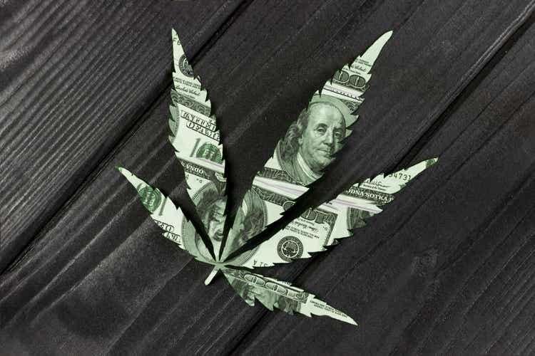 concept, cannabis leaf made of dollars on wooden background