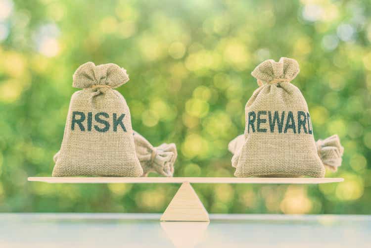 Risk reward ratio / risk management concept: Risk and reward bags on a basic balance scale in equal position, depicts investors use a risk reward ratio to compare the expected return of an investment