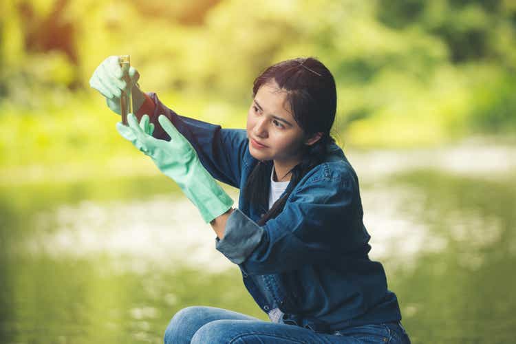 Asiatische weibliche Arbeitskontrolle Kontrolle der Qualität des Wassers mit Glasrohr.