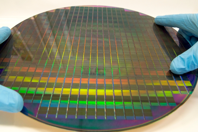 Two Gloved Hands Holding a Patterned 12 Inch 300 mm Silicon Wafer Against a White Background