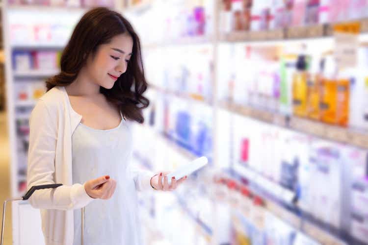 Young Asian woman choosing cosmetic cream in beauty shop