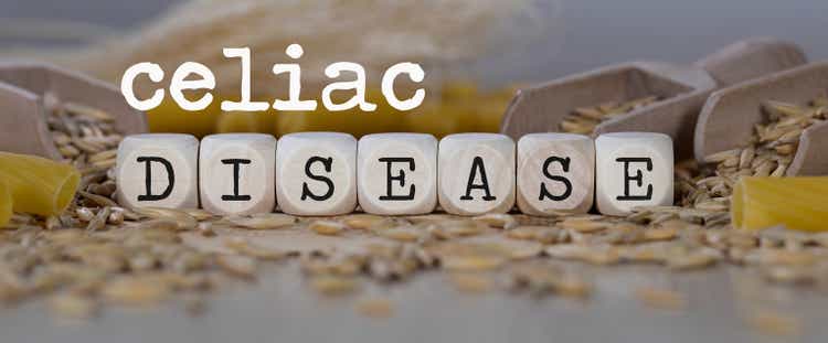 Words CELIAC DISEASE composed of wooden dices. Rye grains in the background.