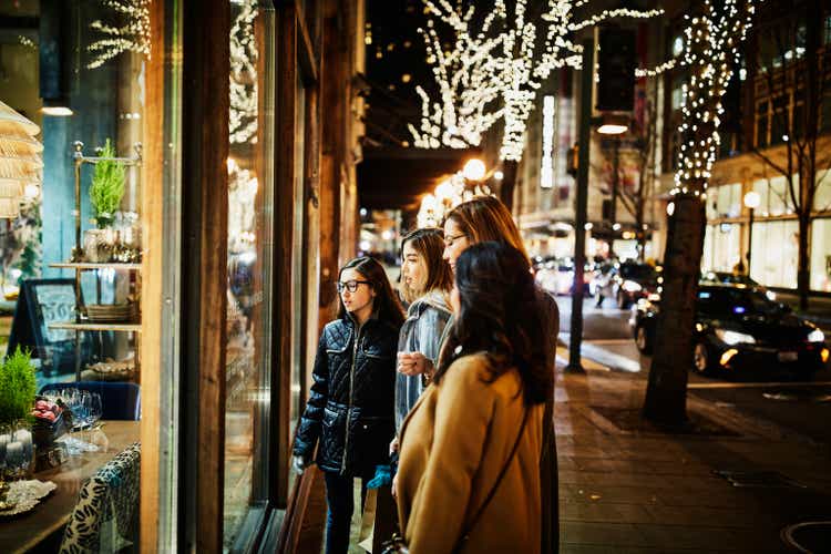 Two mature women and teenage daughters window shopping during holidays