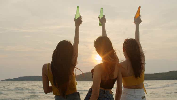 Group of Asian teenage girls having party celebrating on beach, friends happy drinking beer on beach at sea when sunset in evening. Outdoor activity friends travel holiday vacation summer concept.