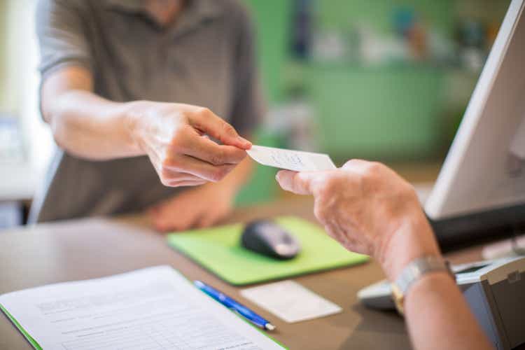 Receptionist giving a health card to female patient at clinic