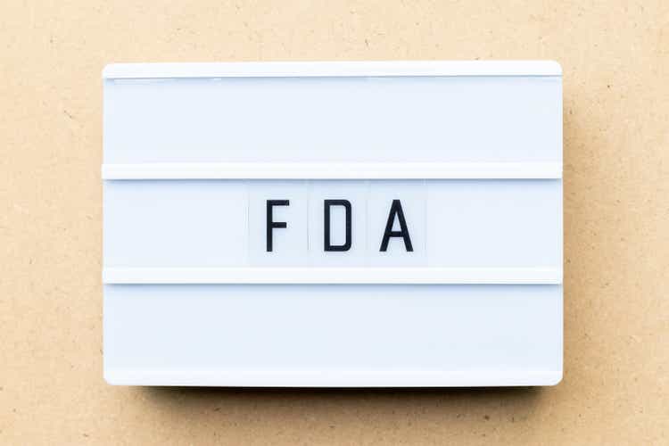 White lightbox with word FDA (abbreviation of food and drug administration) on wood background