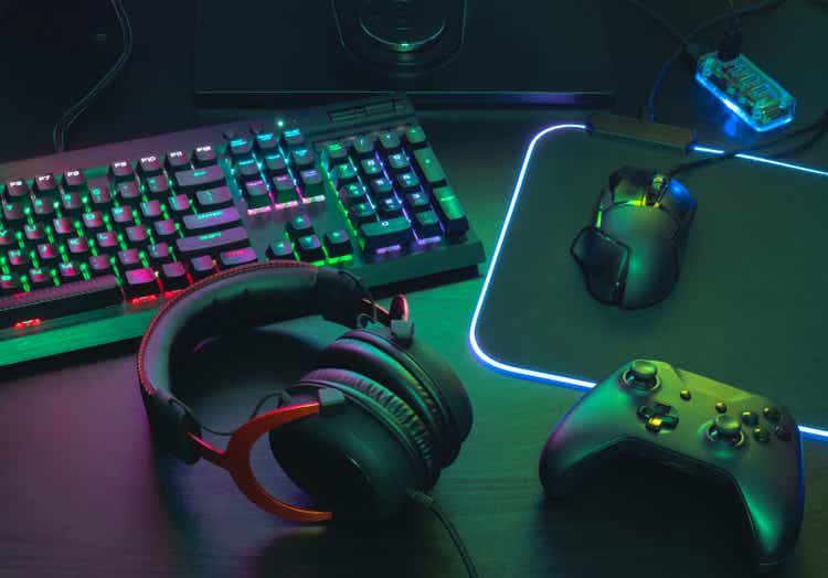 gamer work space concept, top view a gaming gear, mouse, keyboard, joystick, headset, mobile joystick, in ear headphone and mouse pad on black table background.